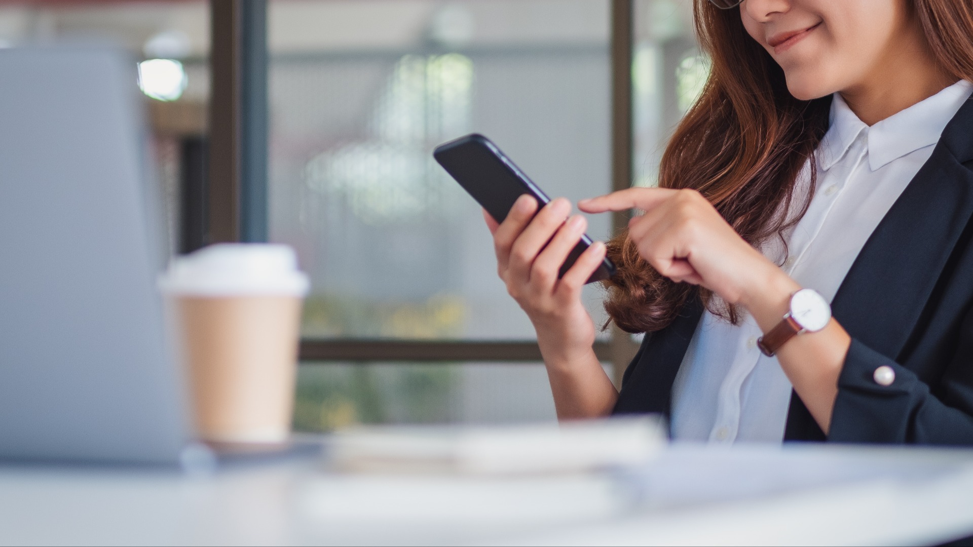 Nahaufnahme einer Geschäftsfrau, die ein Mobiltelefon im Büro benutzt